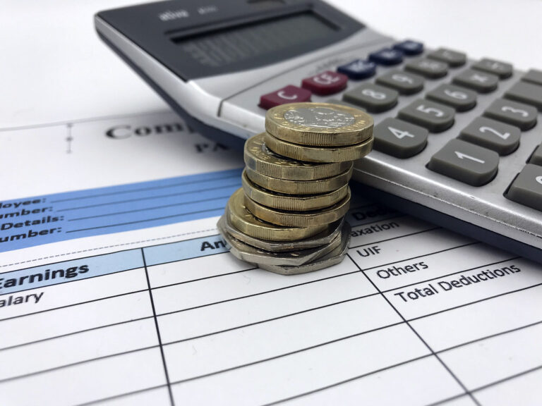 calculadora com moedas e notas empilhadas
