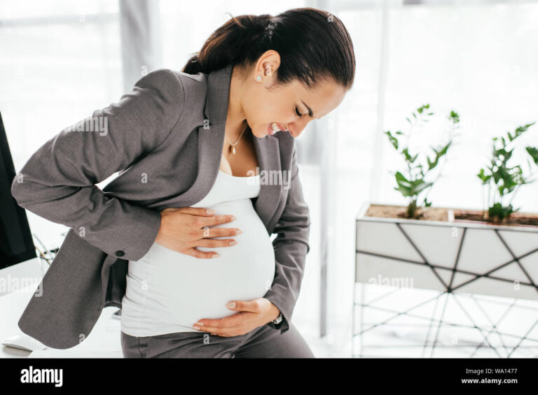 Descobri que estou grávida: Posso ser demitida no trabalho 14 mae gravida segurando a barriga em escritorio