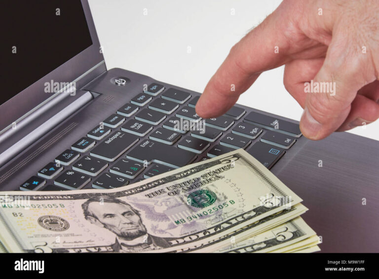 maos digitando em um laptop com dinheiro