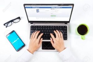 maos digitando em um laptop com facebook