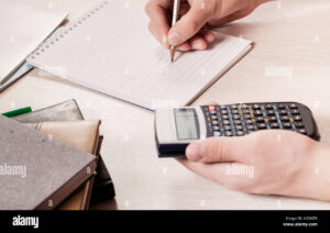 maos segurando uma calculadora e documentos