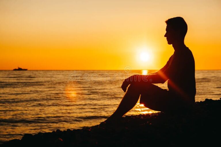 pessoa contemplando uma praia ao por do sol