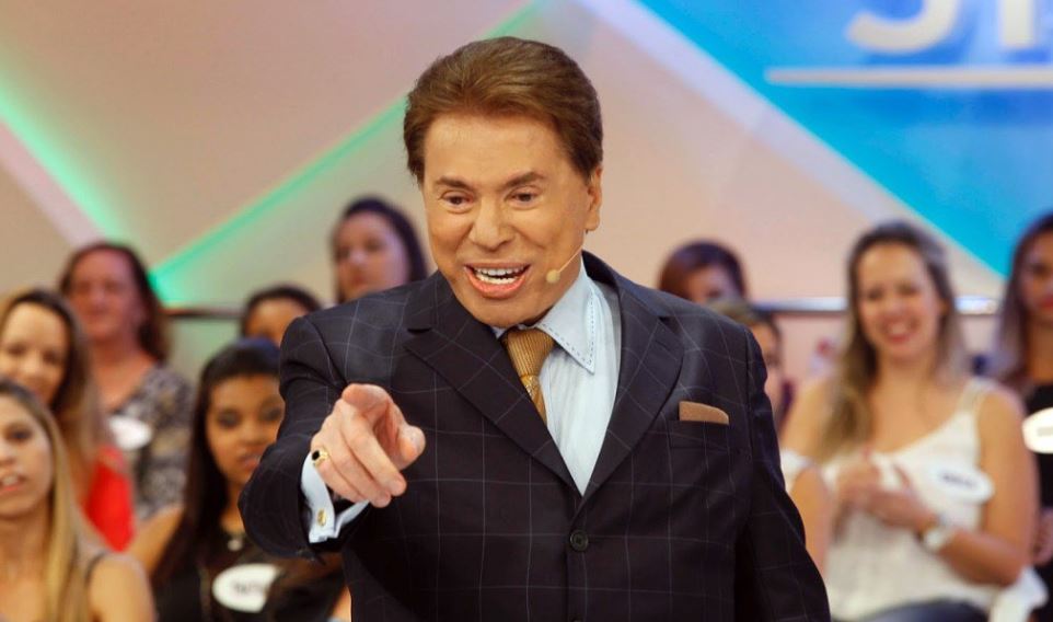 silvio santos rindo em um palco iluminado